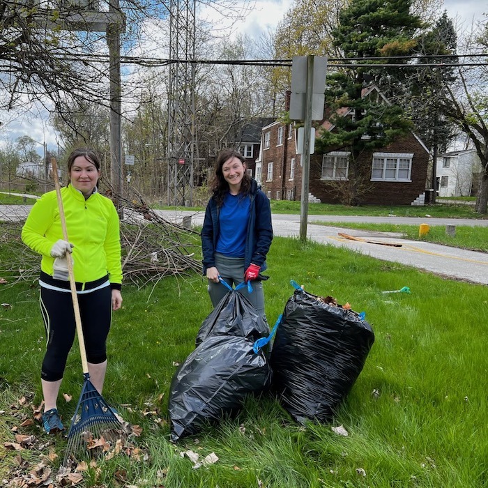two women with garbage bags and rake cleaning trail