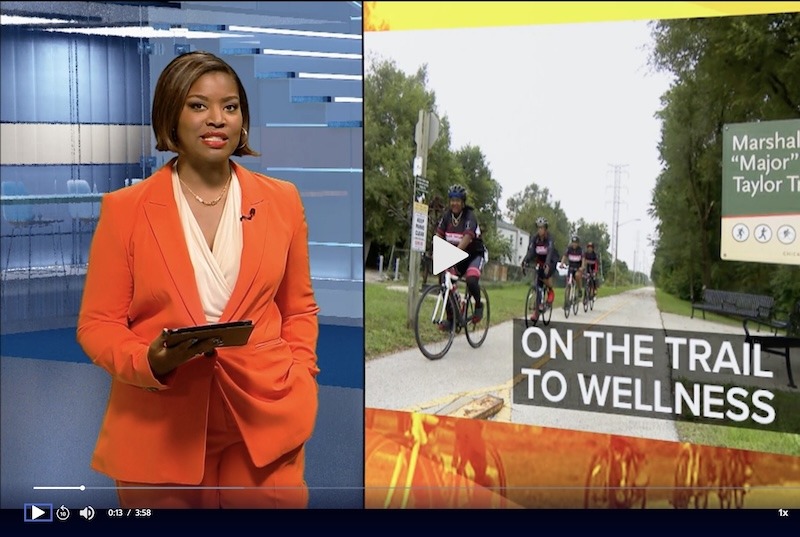 Clickable image of WTTW Chicago Tonight host in orange suit with image of Maj Taylor Trail